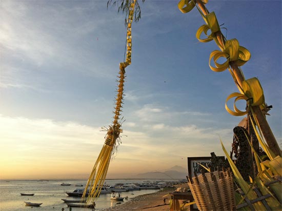 A penjor, some boats and a volcano.