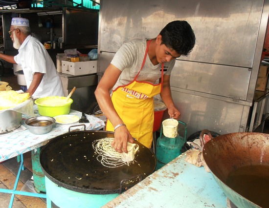 A stallholder making one of the bazaar's more unusual offerings, 'roti jala'.