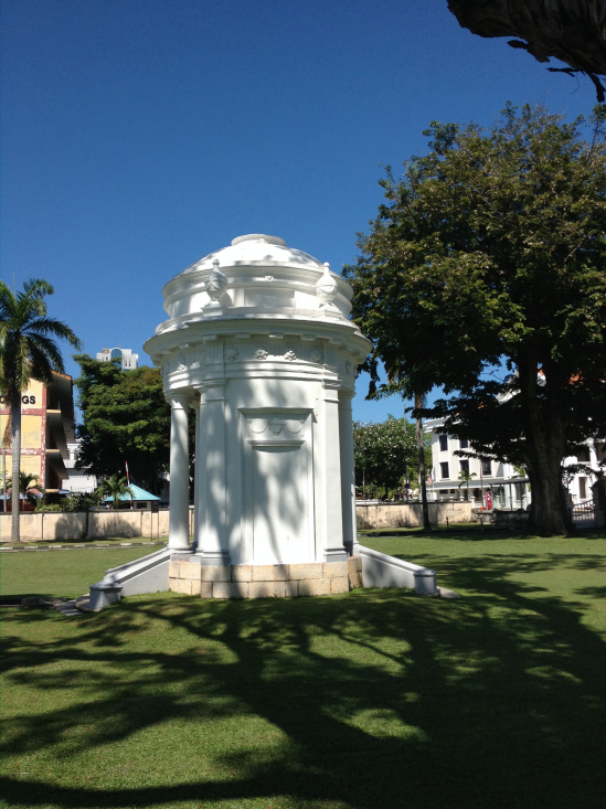 The cenotaph, memorial to Penang's founder, dappled by the shade of a century-old mahogany tree.
