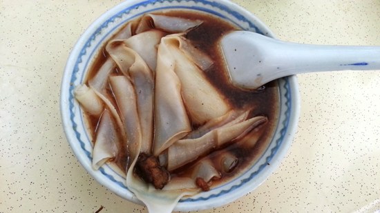 A bowl of 'Kway' - flat rice noodles in a soy-based broth.