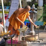 A Forest Tradition monk removes wax from candlesoffered by visitors at Wat Pa Suthawat.