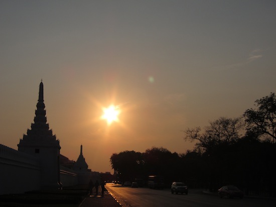 A big sun sets over the gates of the Grand Palace.