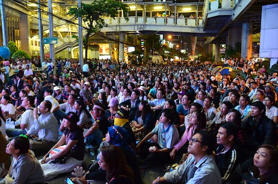 Demonstrators sit on Sukhumvit Road and listen to a speech from leader Suthep.